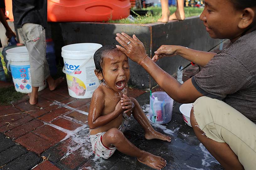 Индонезия, Палу. Женщина моет ребенка в лагере для пострадавших от землетрясения 