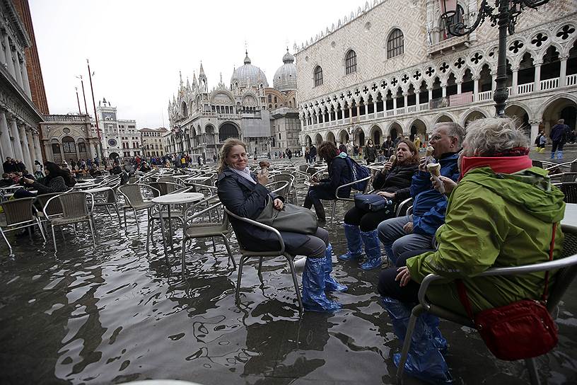 Венеция, Италия. Туристы едят мороженое на затопленной площади Святого Марка 