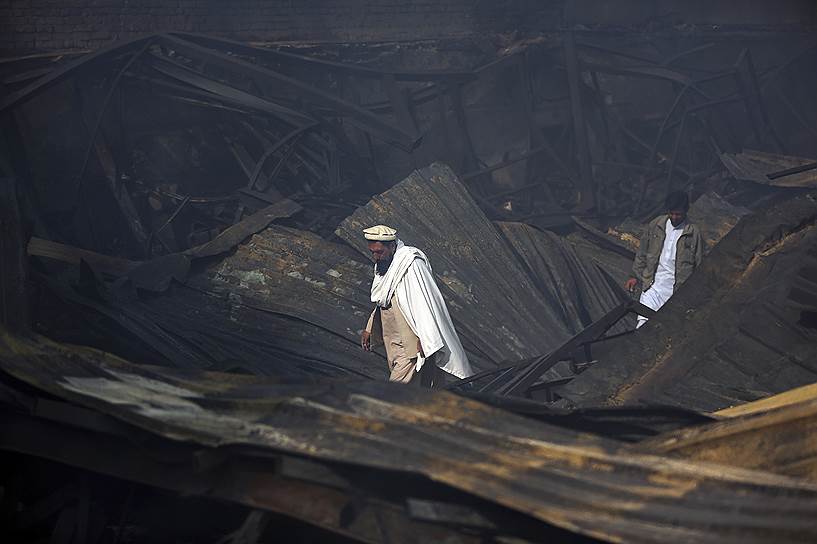 Кабул, Афганистан. Мужчины бродят по развалинам сгоревшего рынка
