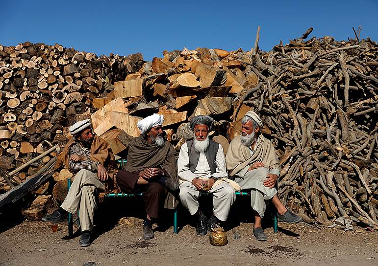 Кабул, Афганистан. Местные жители сидят у поленницы

