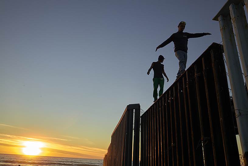 Тихуана, Мексика. Мигранты ходят по забору между Мексикой и США
