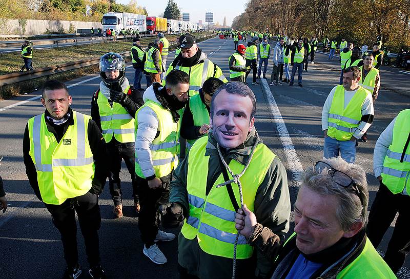 Протестующий в маске, изображающей президента Франции Эмманюэля Макрона