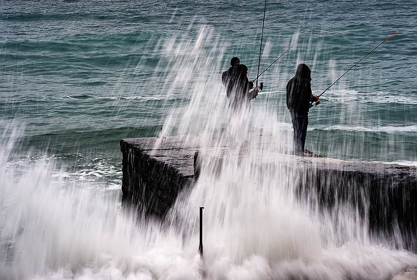Крым. Рыбаки с удочками на волнорезе во время шторма