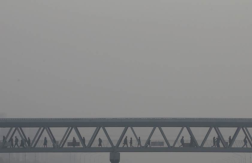 Пекин, Китай. Местные жители идут по мосту сквозь смог
