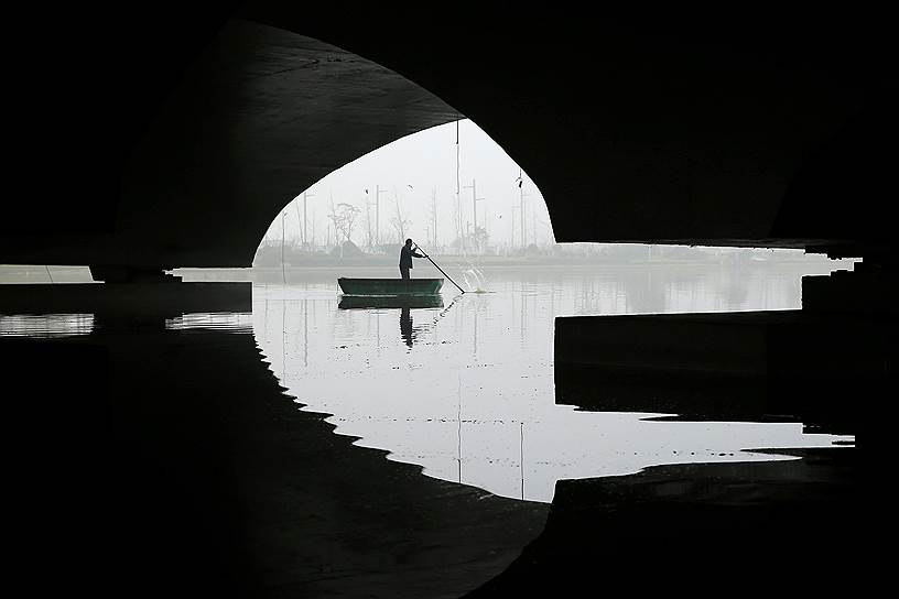 Ляньюньган, Китай. Мужчина плывет на лодке после введения оранжевого уровня опасности из-за сильного смога 
