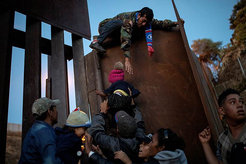 Тихуана, Мексика. Мигранты из Гондураса пытаются добраться до США, перелезая через пограничный забор