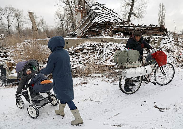 Волгоград, Россия. Женщина с ребенком и мужчина на велосипеде на фоне разрушенного деревянного дома