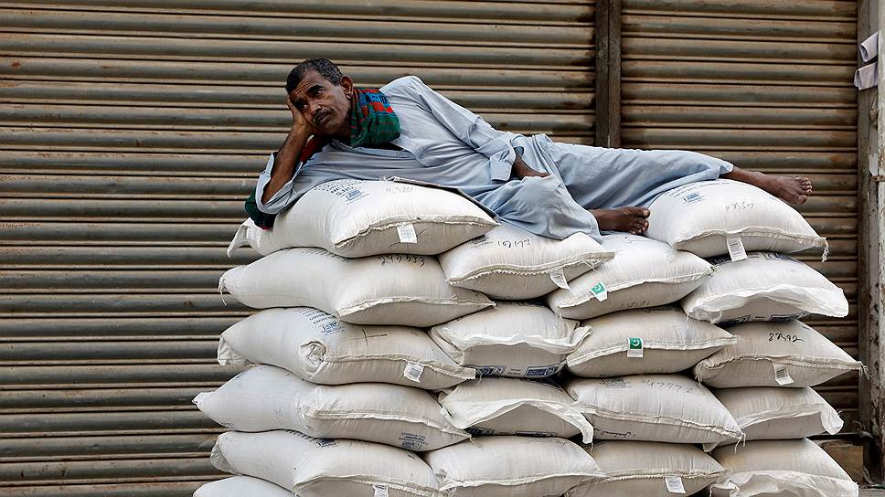 Карачи, Пакистан. Работник отдыхает на мешках с сахаром перед магазином, ожидая открытия