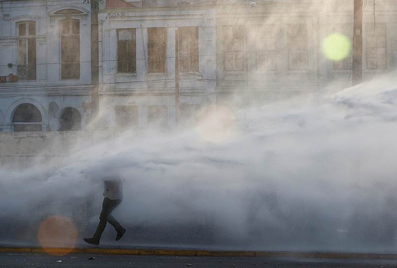 Вальпараисо, Чили. Полиция обливает водой сотрудников порта, протестующих против компании TPS 
