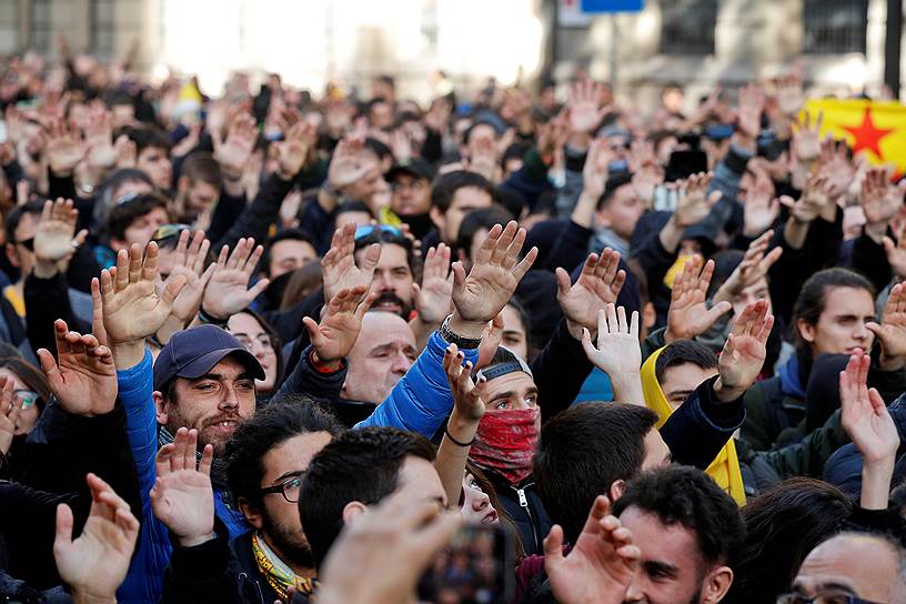 Люди поднимают руки в знак протеста против заседания испанских министров в Барселоне