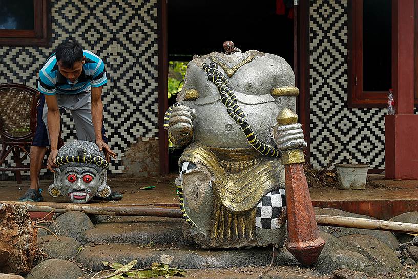 Рабочий поднимает голову разрушенной статуи в одном из отелей в провинции Бантен