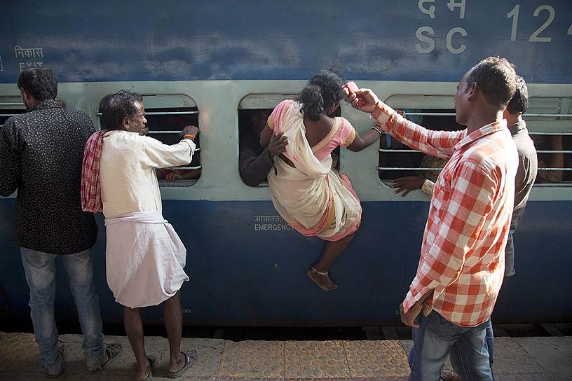 Хайдарабад, Индия. Женщина залезает в поезд через окно