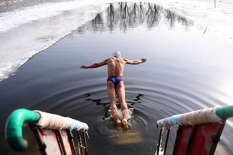 Шэньян, провинция Ляонин, Китай. Мужчина ныряет в прорубь