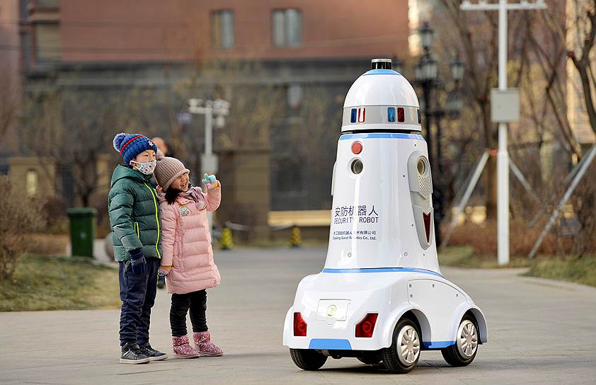 Хух-Хото, Китай. Дети смотрят на робота, занимающегося патрулированием района
