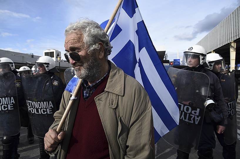 Протестующий c флагом Греции в окружении полиции