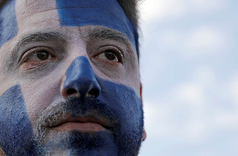 Участник акции протеста раскрасил лицо в цвета греческого флага
