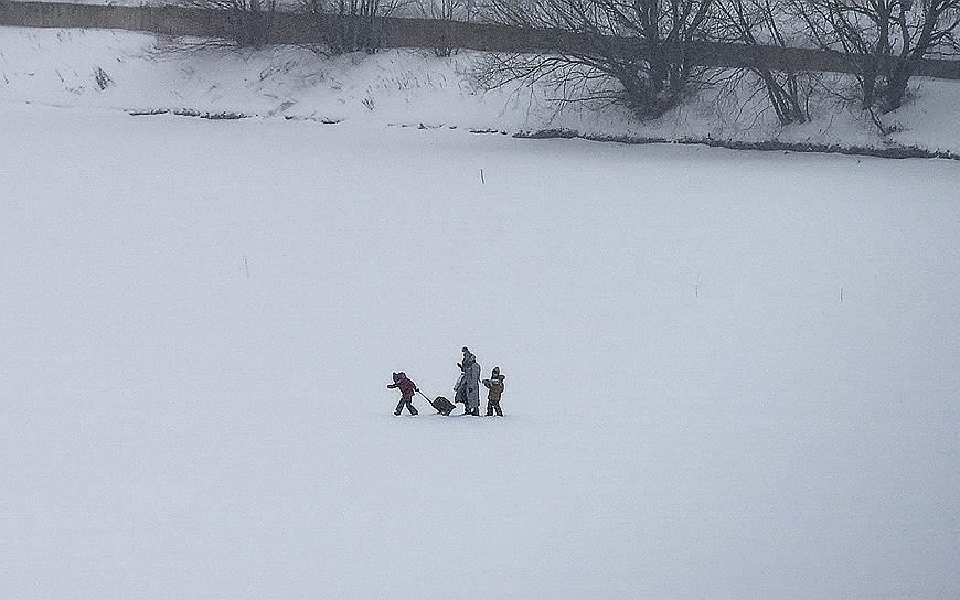 Женщина во время прогулки с детьми на льду Москвы-реки