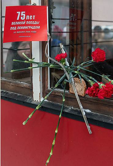 Букет красных гвоздик и кусок хлеба на окне трамвая во время исторической реконструкции жизни блокадного Ленинграда
