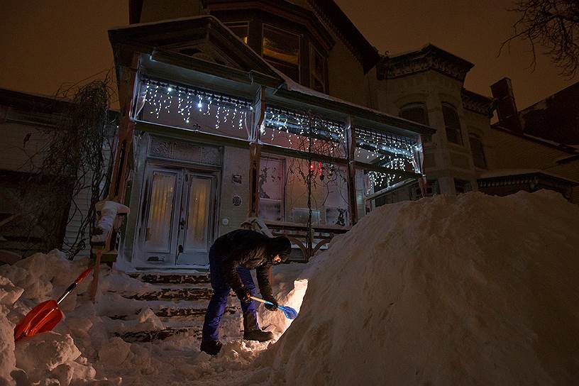 Буффало, Нью-Йорк. Мужчина убирает снег перед домом 