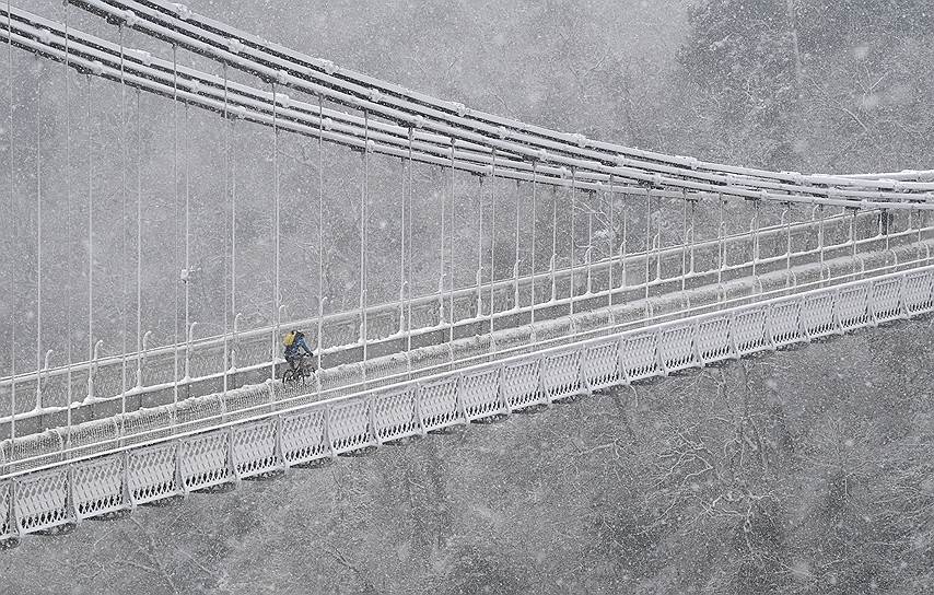 Бристоль, Великобритания. Велосипедист едет по Клифтонскому мосту во время снегопада