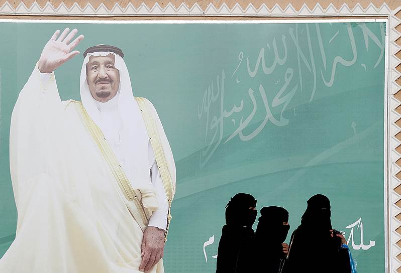 Эр-Рияд, Саудовская Аравия. Женщины проходят мимо плаката с изображением короля Салмана ибн Абдул-Азиза Аль Сауда во время фестиваля исламской культуры 
