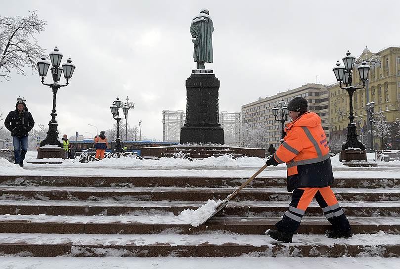 Сотрудник коммунальной службы в оранжевом жилете во время уборки снега на Пушкинской площади