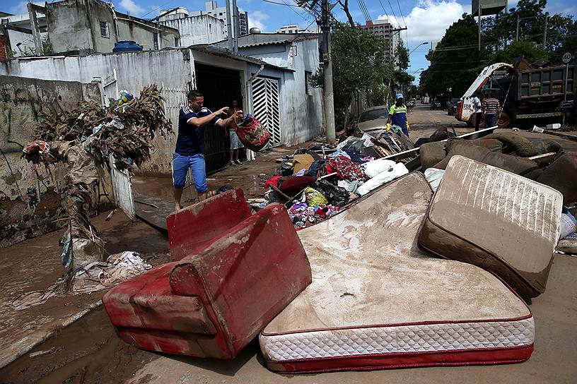 Сан-Каэтану-ду-Сул, Бразилия. Мужчина выбрасывает вещи, поврежденные во время наводнения