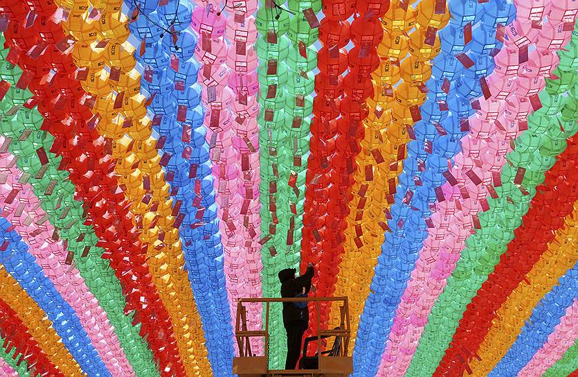 Сеул, Южная Корея. Рабочий прикрепляет к фонарю бирку с именем буддиста, который сделал пожертвование для предстоящего празднования дня рождения Будды 