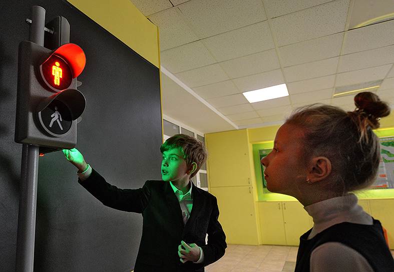 Москва, Россия. Ученики начальной школы знакомятся с работой светофора на пешеходном переходе
