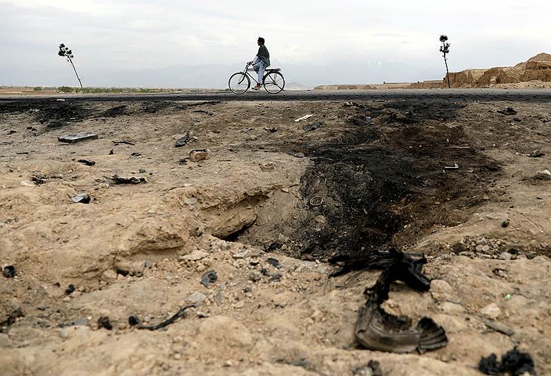 Баграм, Афганистан. Афганец проезжает на велосипеде мимо места взрыва 
