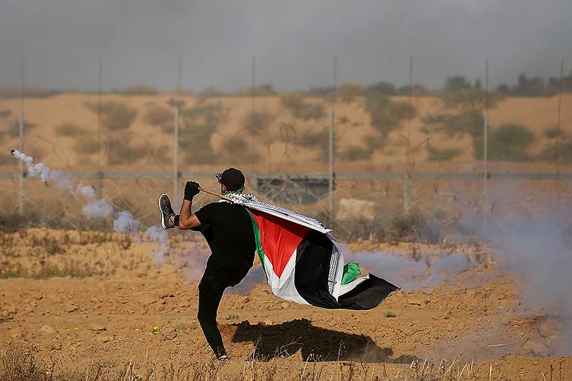 Сектор Газа. Палестинский демонстрант пинает шашку со слезоточивым газом обратно в сторону израильских военных