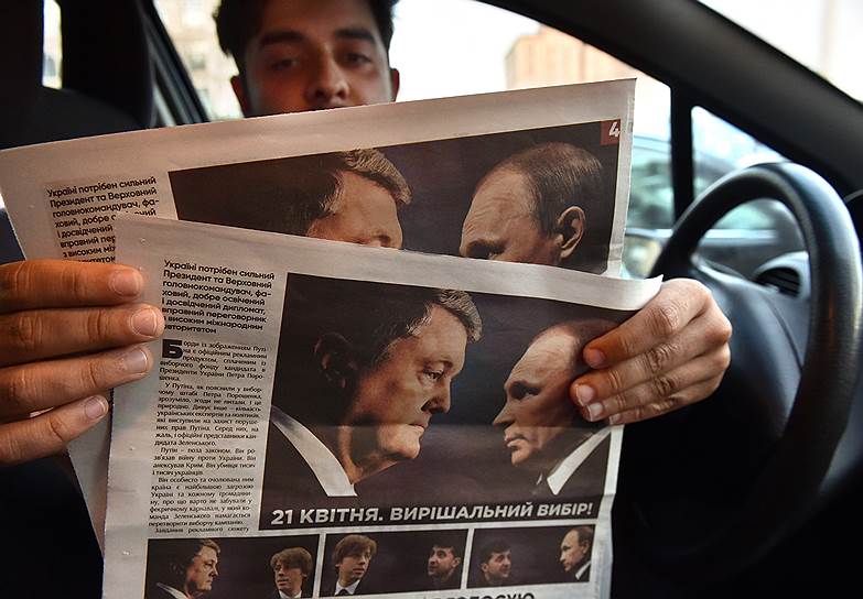 Газета с фотографией Петра Порошенко и Владимира Путина в руках у водителя автомобиля