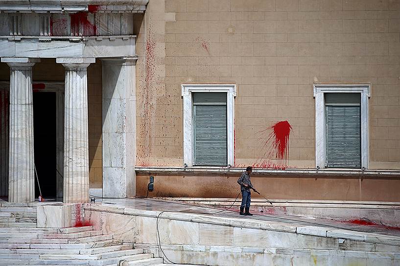 Афины, Греция. Рабочий отмывает краску, которую неизвестные бросили в здание парламента