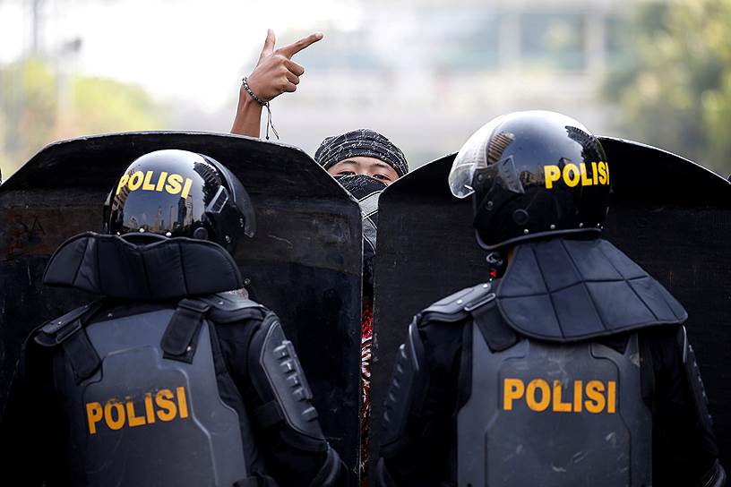 Джакарта, Индонезия. Протестующий стоит перед полицейскими 