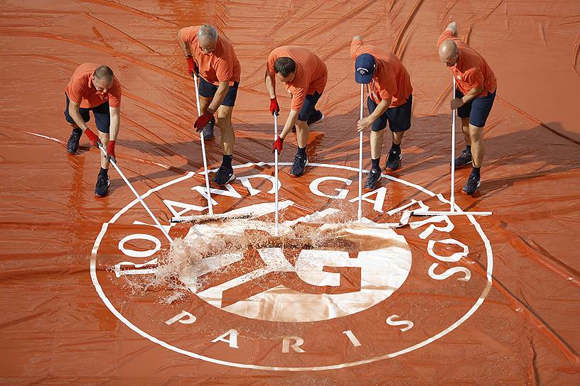 Париж, Франция. Работники чистят корт после ливня во время четвертьфинальных матчей Roland Garros