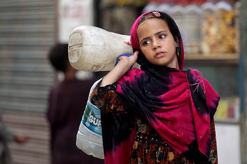 Лахор, Пакистан. Афганская девочка-беженка несет пустые бутыли 