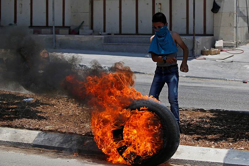 Западный берег реки Иордан. Палестинский мальчик рядом с горящей шиной во время акции протеста против организованной США конференции по Палестине в Бахрейне