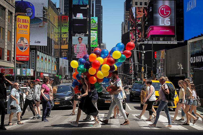Нью-Йорк, США. Женщина идет по Таймс-сквер со связкой воздушных шаров
