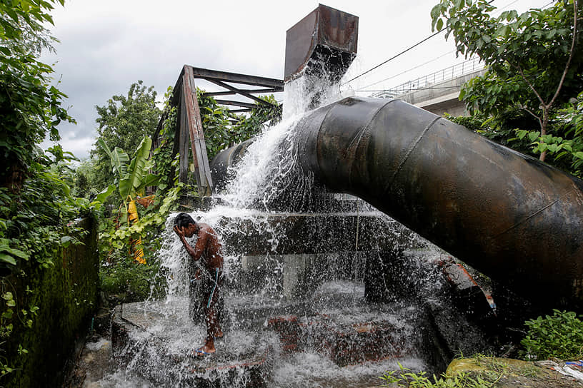 Колката, Индия. Мужчина принимает душ из сломанной водопроводной трубы
