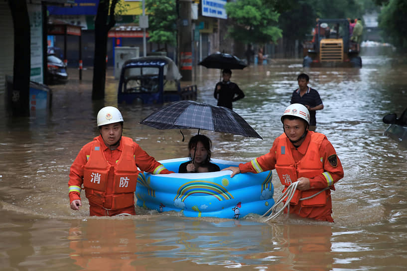 Пинсян, Китай. Спасатели эвакуируют женщину после наводнения