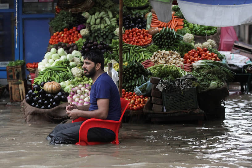 Лахор, Пакистан. Торговец овощами ждет покупателей во время наводнения