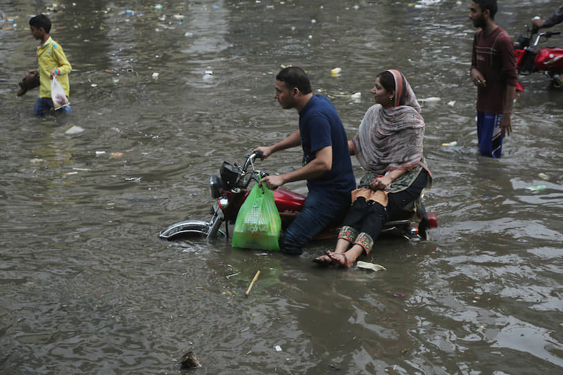 Лахор, Пакистан. Мотоциклист едет по затопленной улице