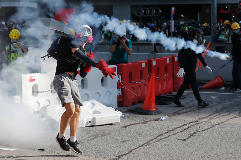 Гонконг, Китай. Протестующий во время антиправительственной забастовки отбрасывает от себя баллон со слезоточивым газом 