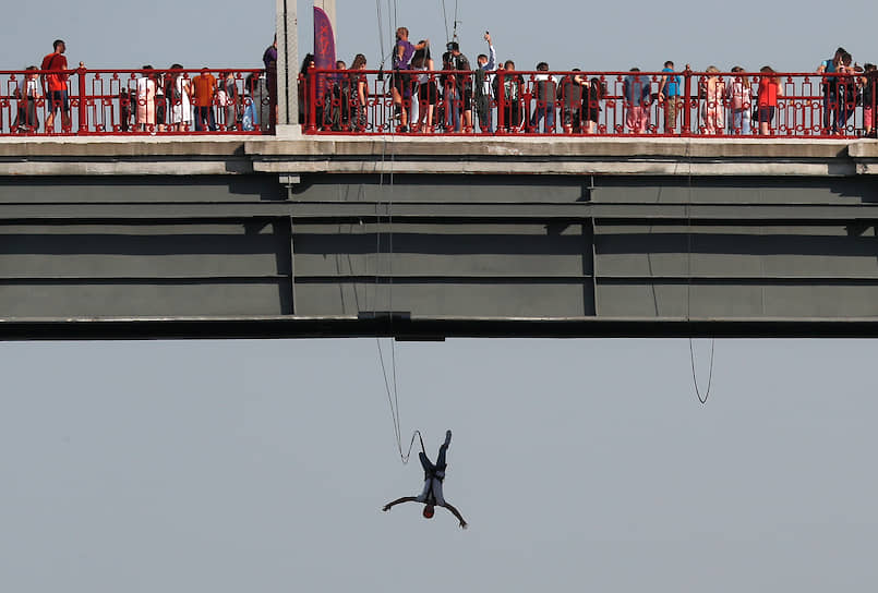 Киев, Украина. Мужчина, привязанный резинкой, прыгает с моста через Днепр