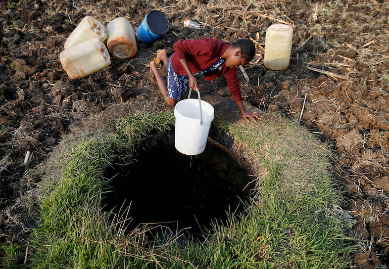 Хараре, Зимбабве. Девушка черпает воду из колодца в местном парке