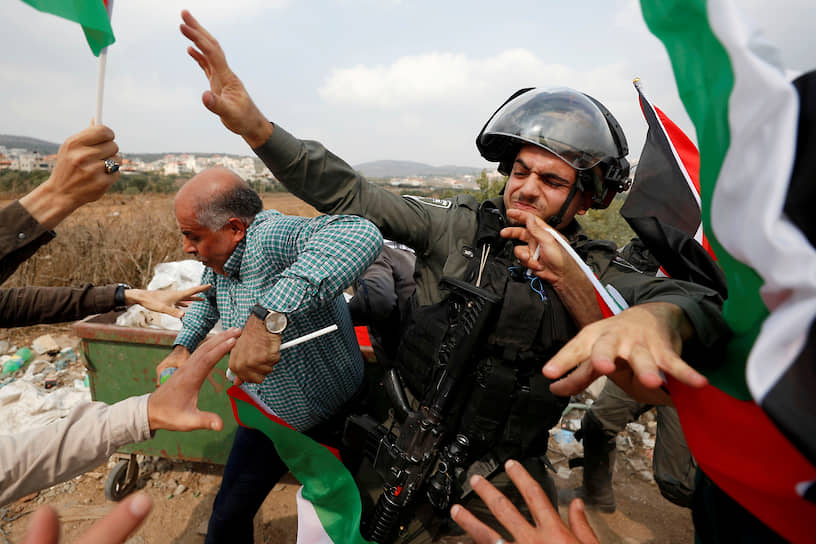 Рамалла, Западный берег реки Иордан. Израильский полицейский и палестинские протестующие 