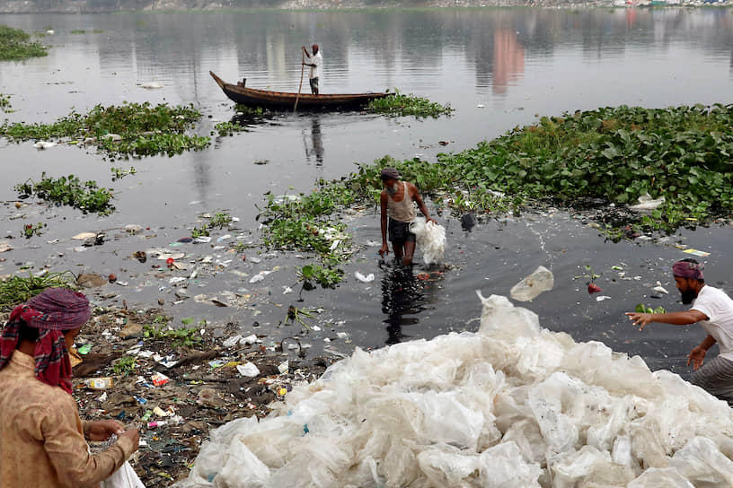 Дакка, Бангладеш. Мужчины моют в реке отходы из пластика перед их утилизацией