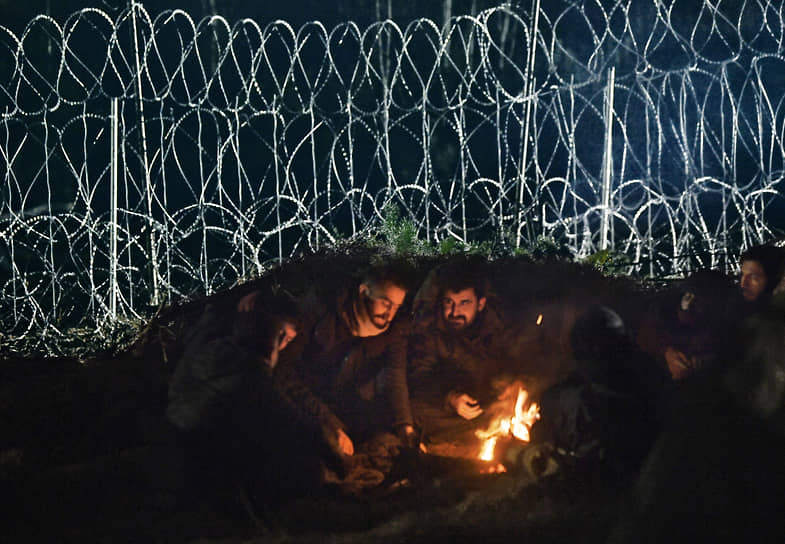 Беженцы у костра в лагере нелегальных мигрантов на белорусско-польской границе