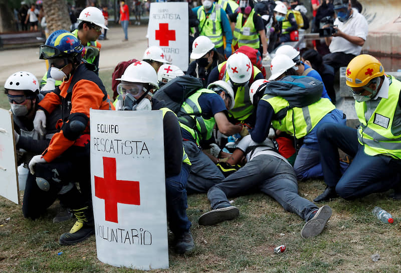 Сантьяго, Чили. Медики помогают пострадавшему демонстранту