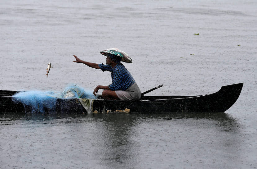 Кочин, Индия. Мужчина ловит рыбу в озере во время дождя